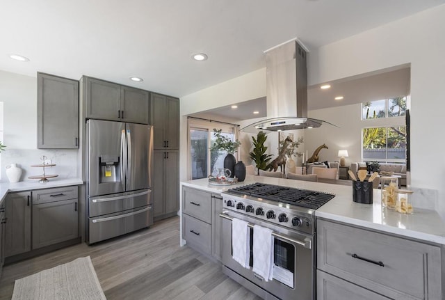 kitchen featuring appliances with stainless steel finishes, light hardwood / wood-style floors, island range hood, and gray cabinets