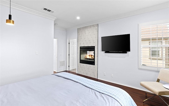 unfurnished bedroom with a multi sided fireplace, crown molding, and dark wood-type flooring