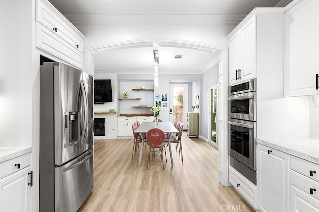 kitchen featuring appliances with stainless steel finishes, light stone counters, ornamental molding, light hardwood / wood-style floors, and white cabinetry