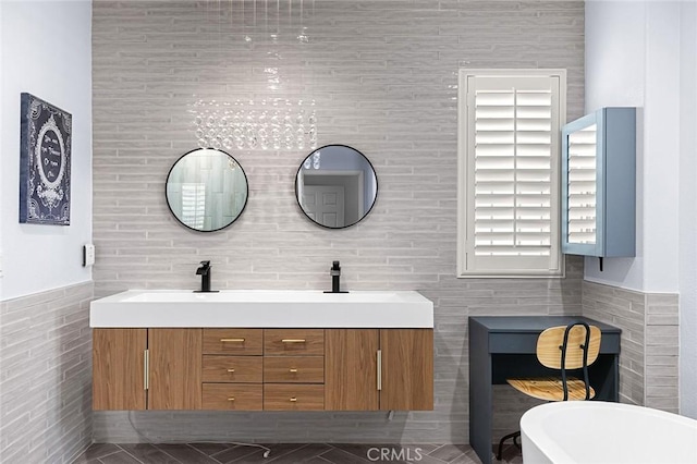 bathroom with a tub, vanity, and tile walls