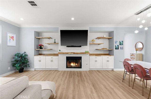 living room with built in shelves, light hardwood / wood-style flooring, and ornamental molding