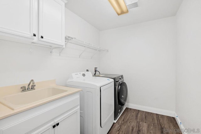 washroom with cabinets, sink, washing machine and dryer, and dark wood-type flooring