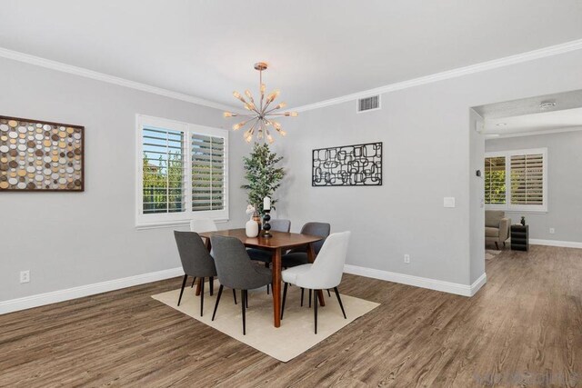 dining room with a wealth of natural light, dark hardwood / wood-style flooring, ornamental molding, and an inviting chandelier