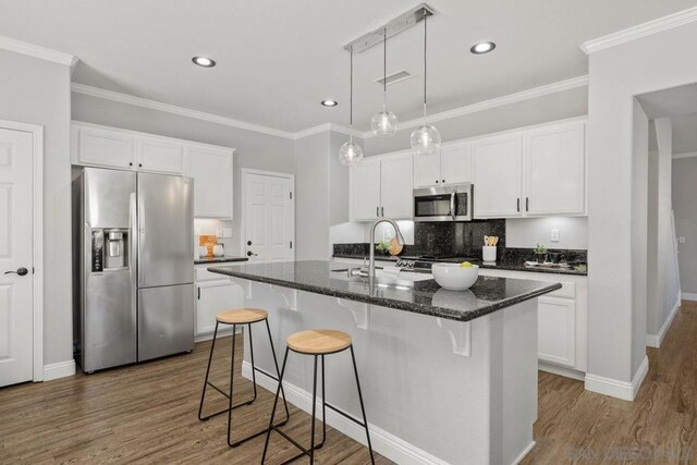 kitchen with white cabinets, appliances with stainless steel finishes, and a center island with sink