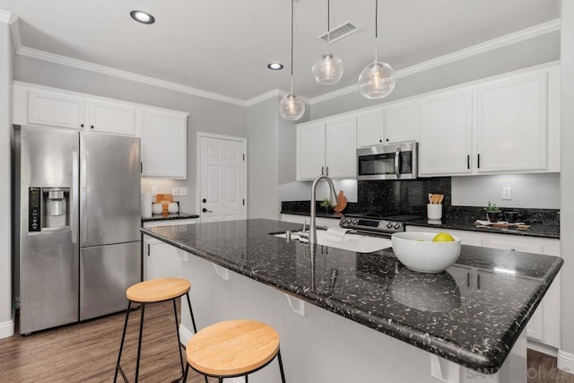 kitchen with stainless steel appliances, white cabinetry, a kitchen island with sink, and crown molding