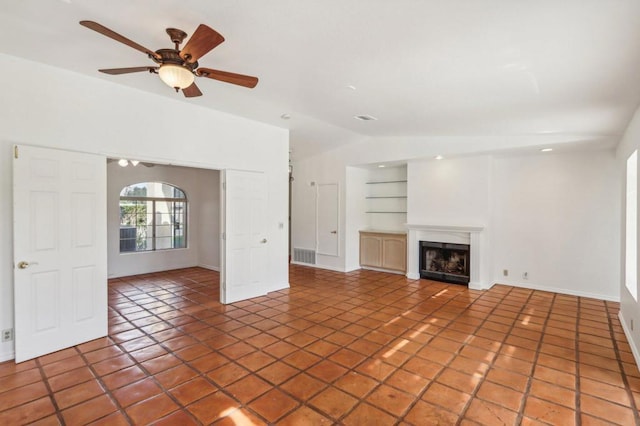 unfurnished living room with tile patterned floors, ceiling fan, and built in shelves