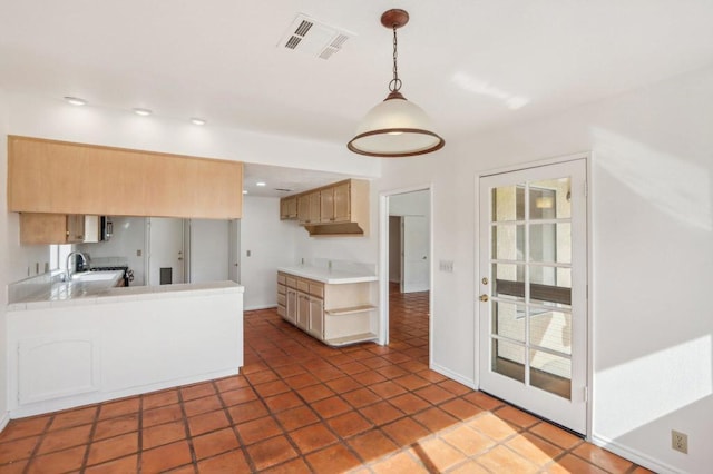 kitchen with pendant lighting, sink, light brown cabinets, and kitchen peninsula