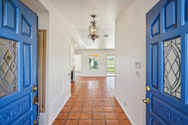 tiled foyer with a chandelier