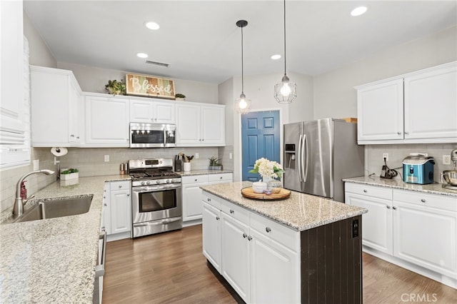 kitchen featuring white cabinets, sink, dark hardwood / wood-style floors, appliances with stainless steel finishes, and decorative light fixtures