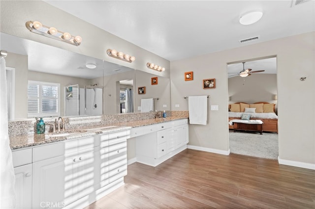 bathroom featuring hardwood / wood-style flooring, vanity, ceiling fan, and a shower