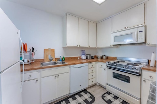 kitchen with white cabinetry, sink, white appliances, and light hardwood / wood-style flooring