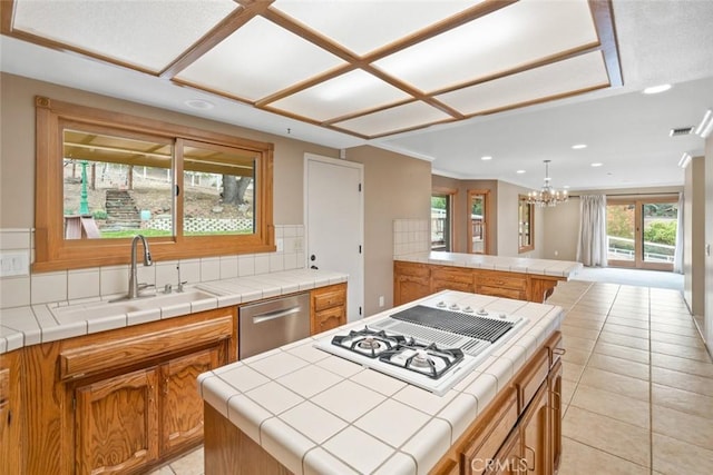 kitchen featuring white gas stovetop, sink, dishwasher, a kitchen island, and tile counters