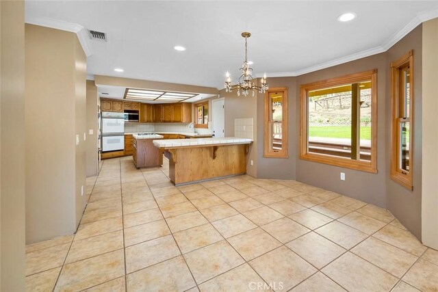 kitchen with sink, kitchen peninsula, crown molding, and a chandelier