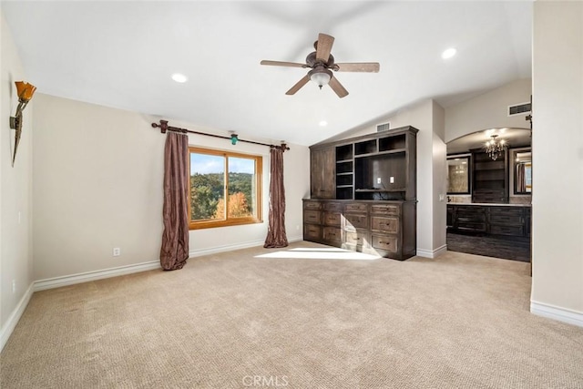 unfurnished living room featuring ceiling fan with notable chandelier, light colored carpet, and lofted ceiling