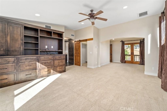 living room featuring light carpet, french doors, a barn door, and ceiling fan