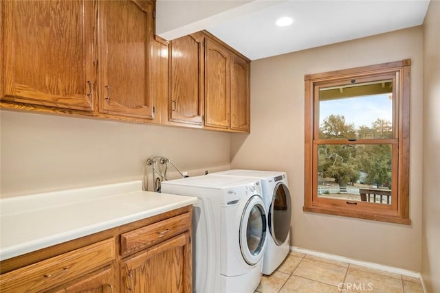 laundry room with washing machine and clothes dryer, light tile patterned floors, and cabinets