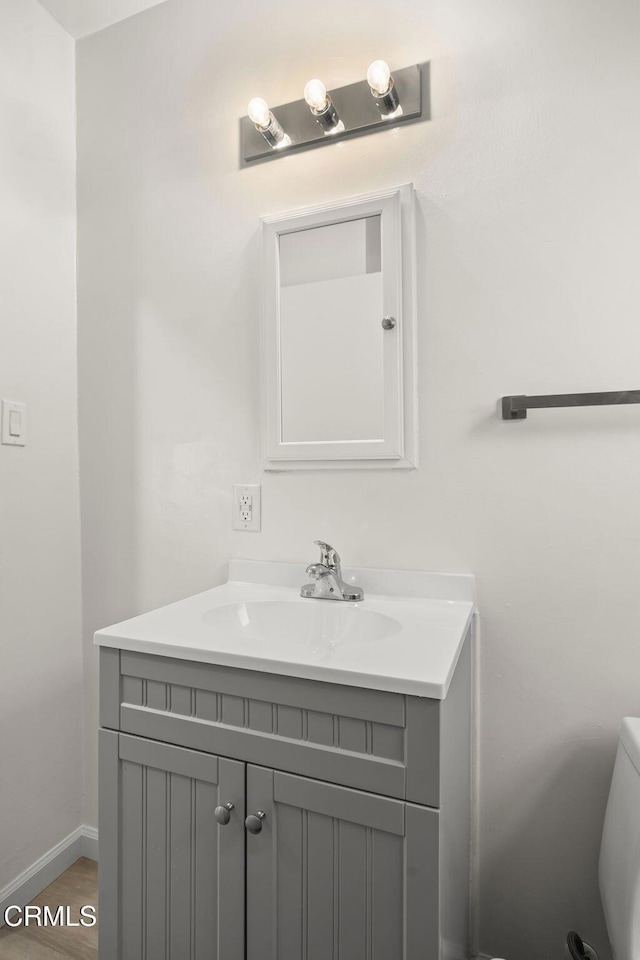 bathroom with hardwood / wood-style flooring, vanity, and toilet