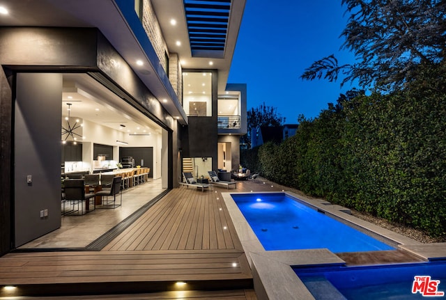 pool at twilight featuring a patio area and a hot tub