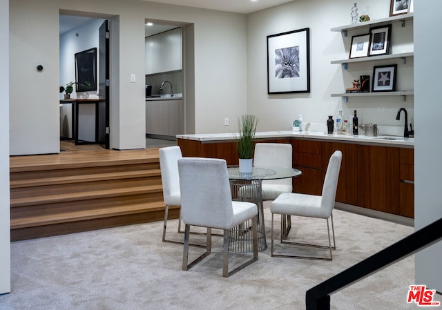 dining area with sink and light colored carpet