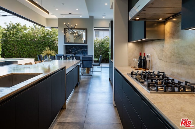 kitchen featuring extractor fan, hanging light fixtures, decorative backsplash, a notable chandelier, and stainless steel gas cooktop