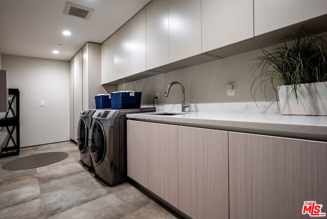 laundry area featuring cabinets, separate washer and dryer, and sink