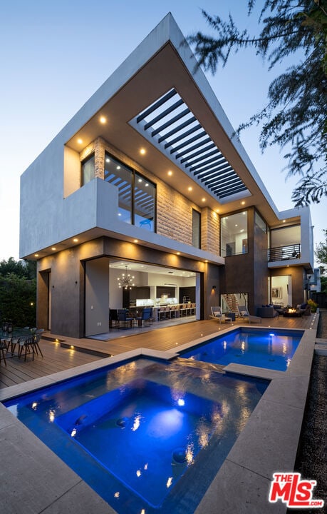 pool at dusk featuring an in ground hot tub and a wooden deck