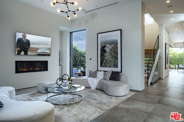 living room with a chandelier, a high ceiling, and concrete floors