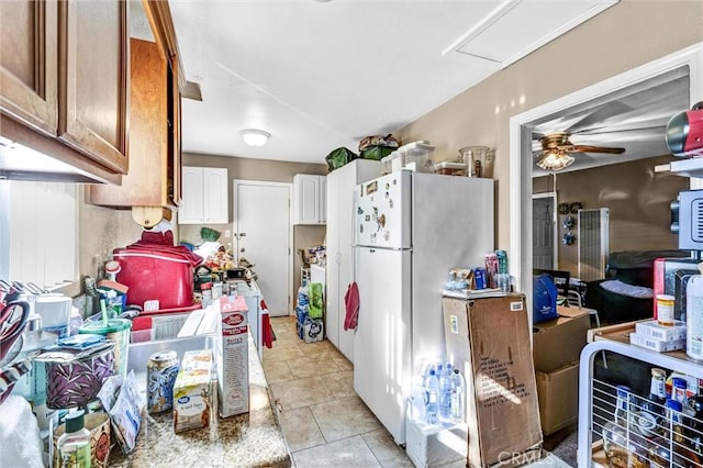 kitchen featuring ceiling fan, light tile patterned floors, white refrigerator, and white cabinetry