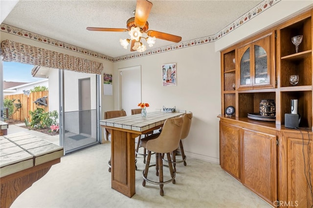 carpeted dining space with ceiling fan and a textured ceiling