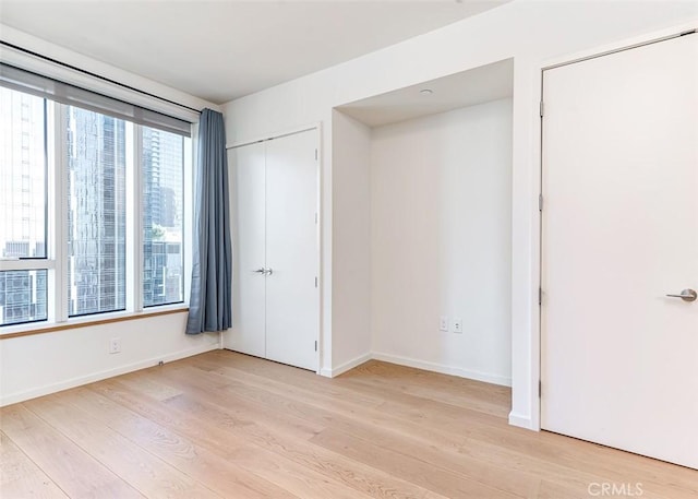 unfurnished bedroom with light hardwood / wood-style floors and multiple windows