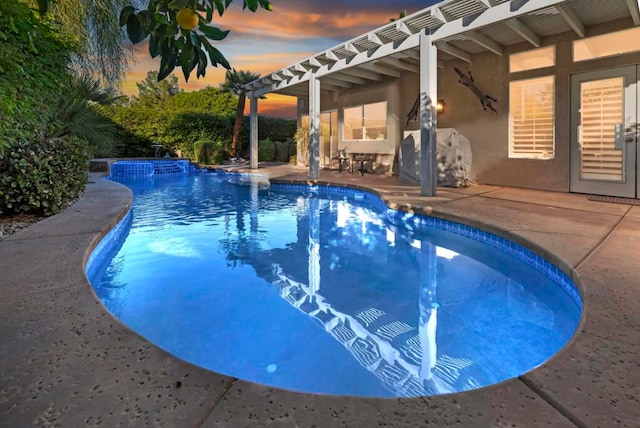 pool at dusk featuring an in ground hot tub and a patio area