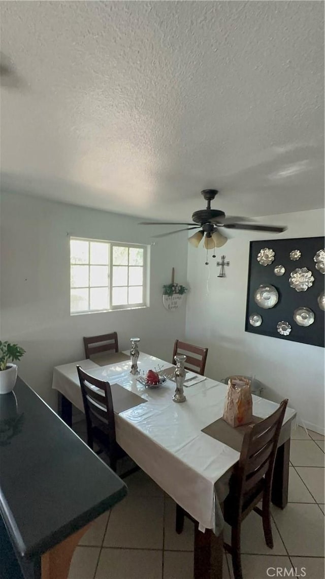 tiled dining room with a textured ceiling and ceiling fan