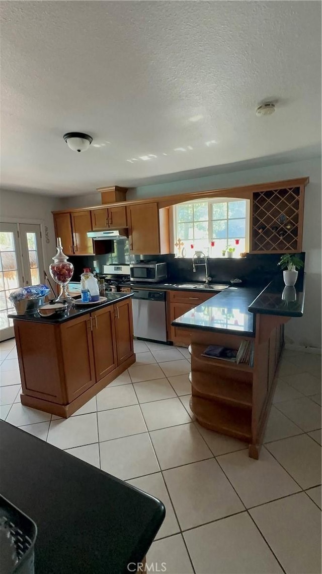 kitchen with sink, light tile patterned floors, stainless steel appliances, and a textured ceiling