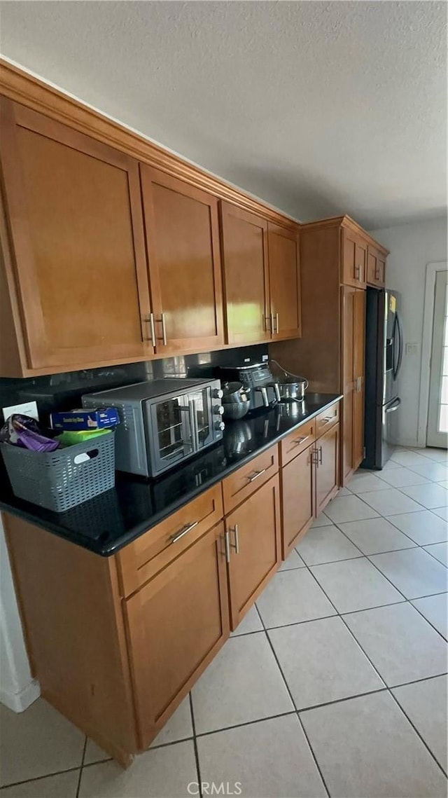 kitchen with light tile patterned floors, a textured ceiling, and stainless steel appliances