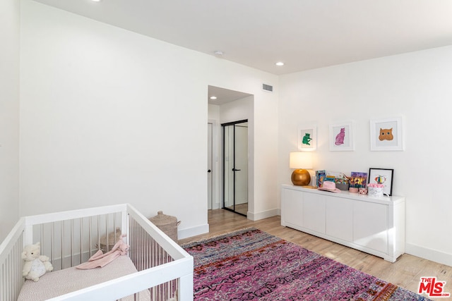 bedroom with a crib and light hardwood / wood-style floors