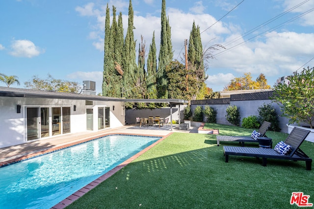 view of pool featuring a patio, a yard, and central AC