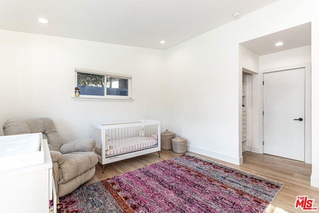 bedroom with light hardwood / wood-style floors and a crib