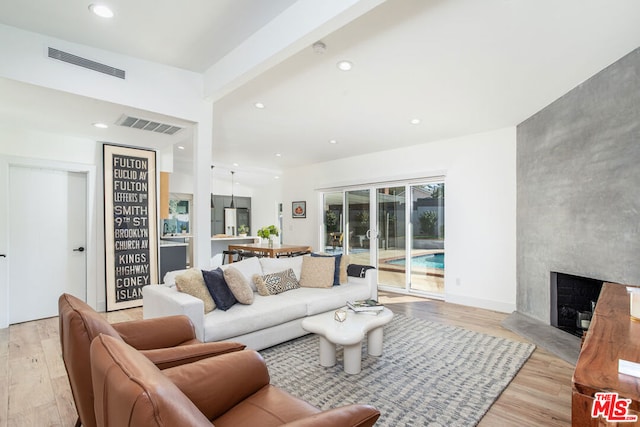 living room featuring a fireplace, beamed ceiling, and light wood-type flooring