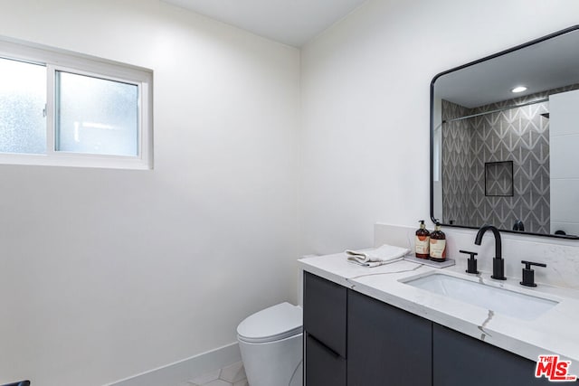 bathroom with tile patterned flooring, vanity, tiled shower, and toilet