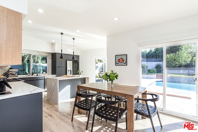 dining room with light wood-type flooring, a healthy amount of sunlight, and sink