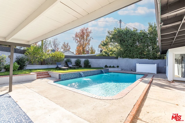 view of pool with pool water feature, a patio, and a lawn