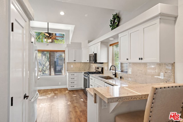 kitchen with sink, hanging light fixtures, stainless steel appliances, kitchen peninsula, and vaulted ceiling