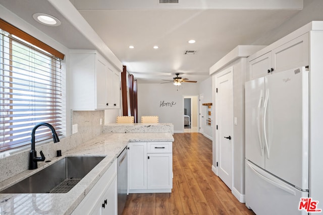 kitchen with kitchen peninsula, light wood-type flooring, sink, white cabinets, and white fridge