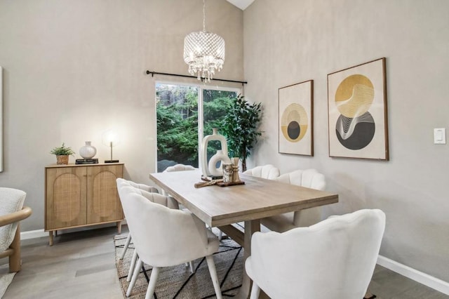 dining area featuring a towering ceiling, a chandelier, and hardwood / wood-style floors