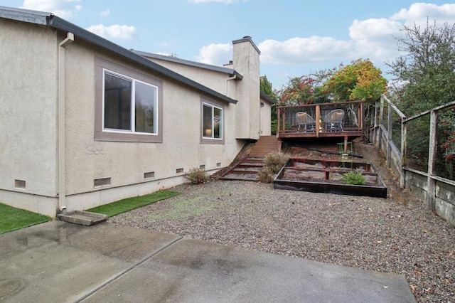 view of side of property featuring a wooden deck and a patio