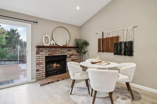 dining area featuring hardwood / wood-style flooring, vaulted ceiling, and a fireplace