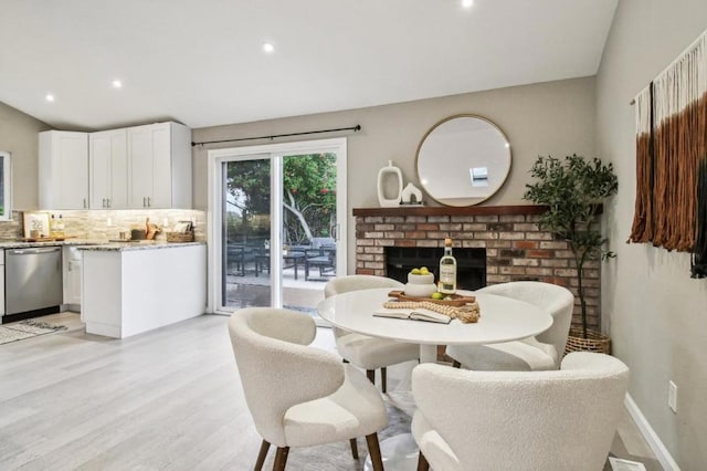 dining space featuring light hardwood / wood-style floors and a brick fireplace