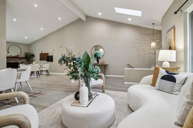 living room with a fireplace, light hardwood / wood-style flooring, and lofted ceiling with skylight