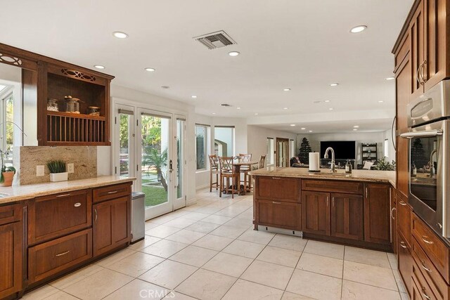 kitchen with sink, light tile patterned floors, oven, and tasteful backsplash