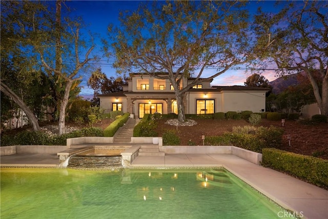 back house at dusk with a patio area and a pool with hot tub